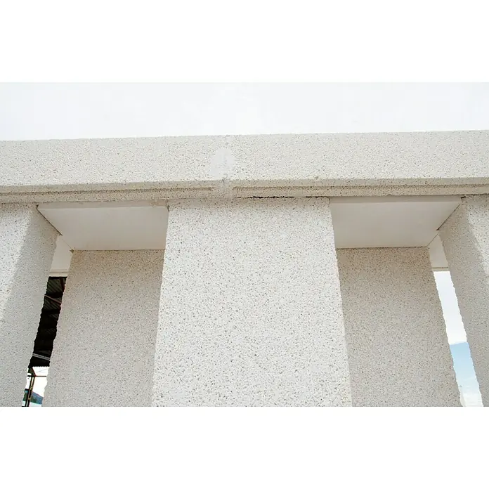 Tapa frontal de protección contra viento - Hormigón polímero, Blanco - Primer plano de la estructura hecha de bloques de hormigón celular. Los bloques AAC son blancos y tienen una superficie porosa con rebajes.