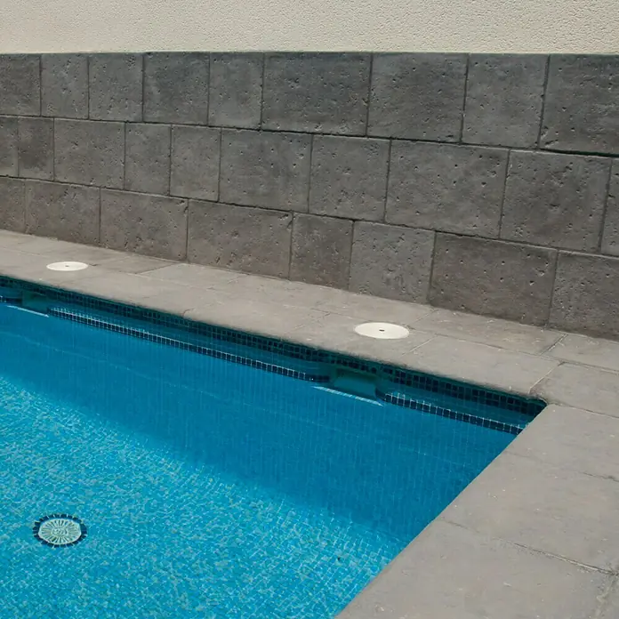 Pavimento remate Piscina Opus Roca - 60 x 50 cm, Gris - Primer plano de una piscina con azulejos de color azul claro y un borde de piscina gris. Cubiertas blancas colocadas a lo largo del borde de la piscina.