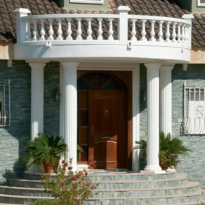 Columna decorativa Grecia - 25 x 30 cm, Blanco - Área de entrada de una casa con una puerta de madera ornamentada, columnas y una balaustrada blanca. Plantas exuberantes adornan la entrada.
