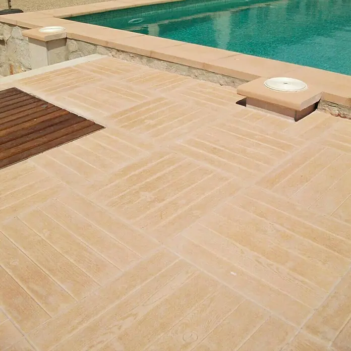 Pavimento para exterior Teka - 50 x 50 cm, Marrón - Terraza de piscina con ladrillos beige en espiga y un elemento de madera, creando un espacio exterior lujoso y moderno.