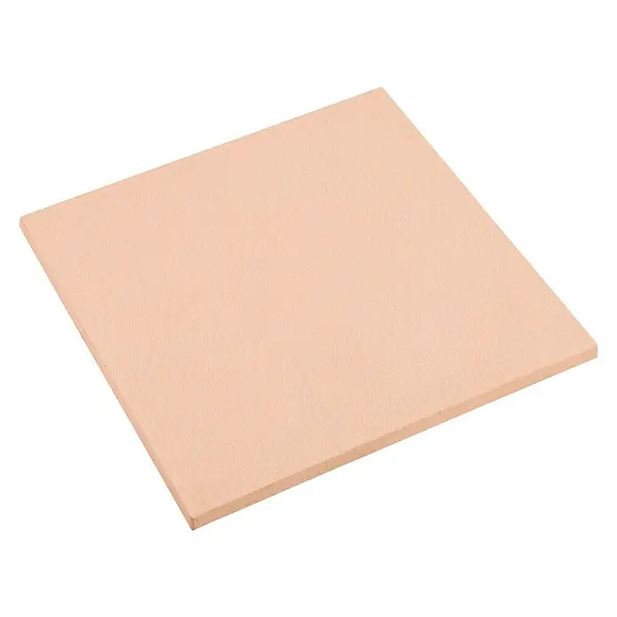 Pavimento para exterior Granulada - 50 x 50 cm, Salmone - Primer plano de una piedra para pizza cuadrada de color rosa claro colocada sobre una superficie blanca. Perfecta para pizzas caseras crujientes.