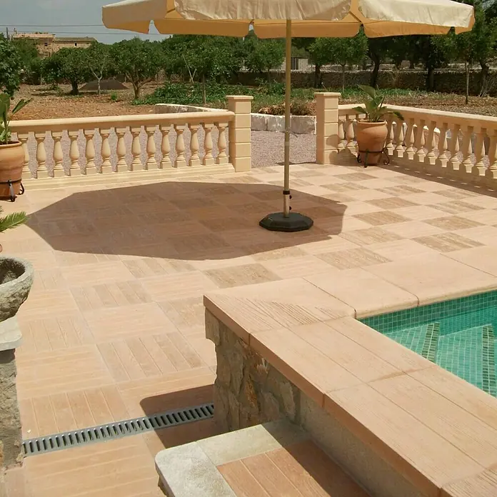 Placas para caminos inverso Teka 5.2 - 45 x 45 x 5 cm, Marrón, Hormigón - Patio acogedor con suelo de baldosas, sombrilla y piscina, perfecto para relajarse al aire libre. Los elementos decorativos añaden un toque especial a la escena.