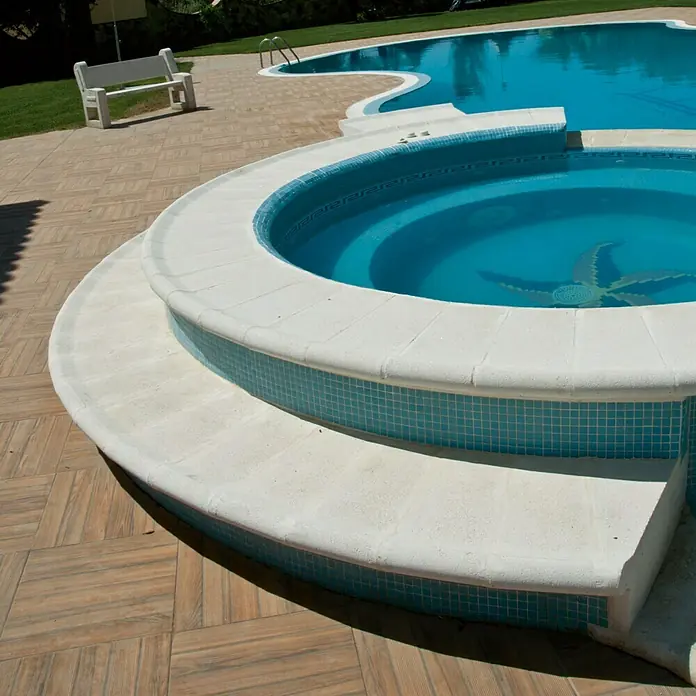 Pavimento remate Piscina R1 - 50 x 25 cm, Blanco - Primer plano de una bañera de hidromasaje redonda con mosaicos turquesas, situada junto a una piscina más grande.