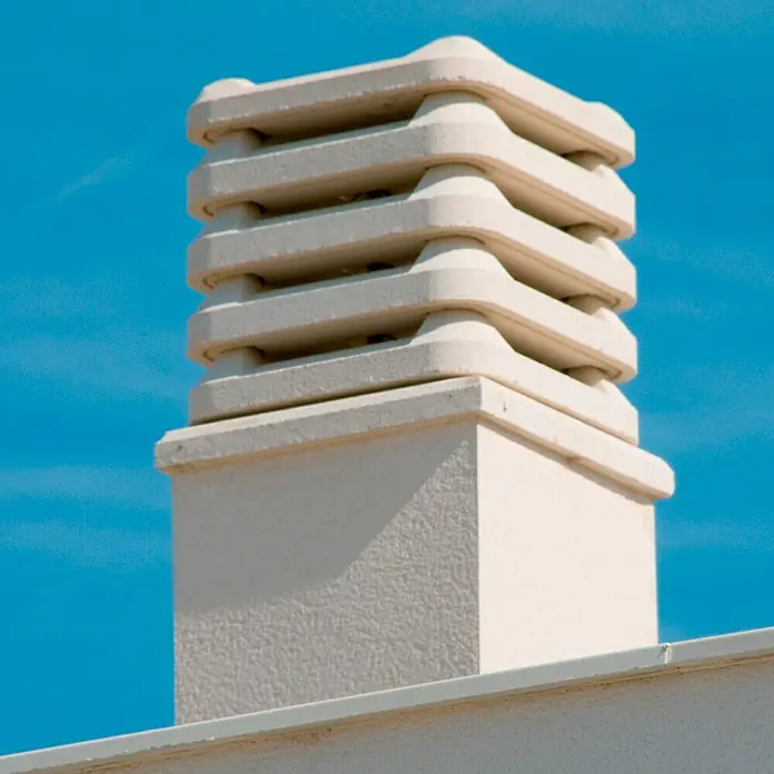 Aspirador estático 50 - Blanco - Primer plano de una chimenea con una cubierta decorativa sobre un cielo azul claro. La estructura blanca destaca visiblemente.