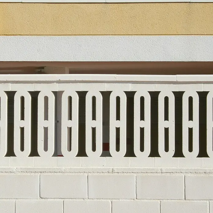 Balaustrada plana - 6 x 20 x 70 cm, Blanco, Hormigón - Primer plano de un muro de hormigón blanco con valla decorativa, destacando elementos arquitectónicos y texturas.