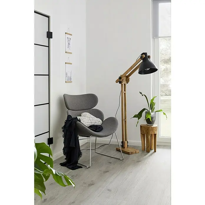 Hocker - Teak, Unbehandelt, Ø x H: 28 x 40 cm - Ein grauer Sessel mit einer Decke und einem Kissen, neben einer Holzstehlampe und einem Beistelltisch mit Pflanze.