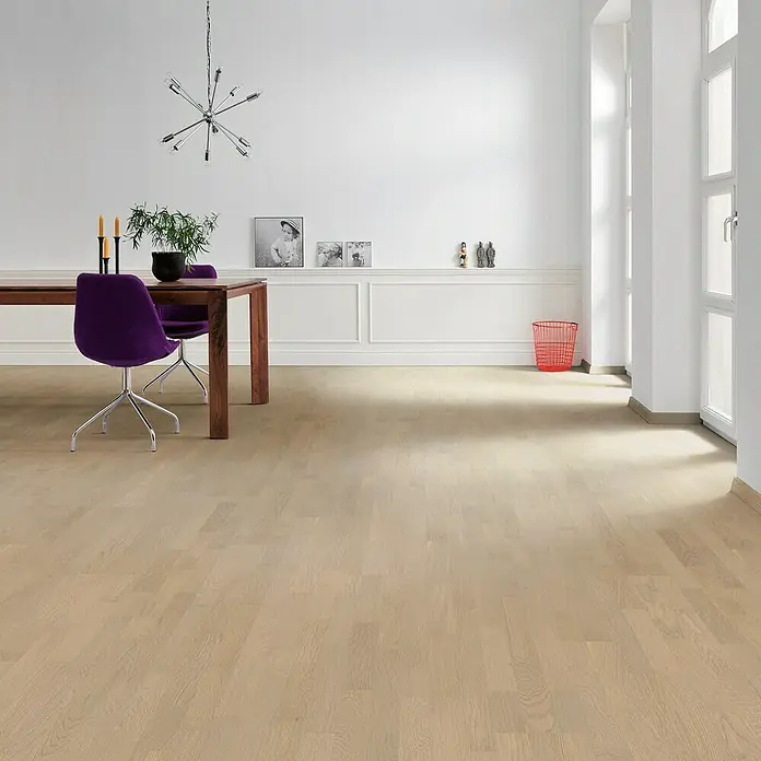 Living by Haro Parkettmuster Eiche Grey versiegelt - 290 x 180 x 12 mm, Schiffsboden - Ein helles, einladendes Esszimmer mit Holzboden, einem Esstisch mit lila Stühlen und einer modernen Lampe.