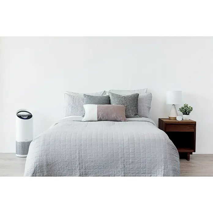 Leitz TruSens Luftreiniger Z-3000Raumgröße: 0 m² - 70 m², SensorPod Luftqualitätsmesser - Schlafzimmer mit Tulips Luftreiniger, Bett, Nachttischlampe und Zimmerpflanze. Der Tulip Luftreiniger sorgt für saubere Luft und eine gesunde Schlafumgebung.