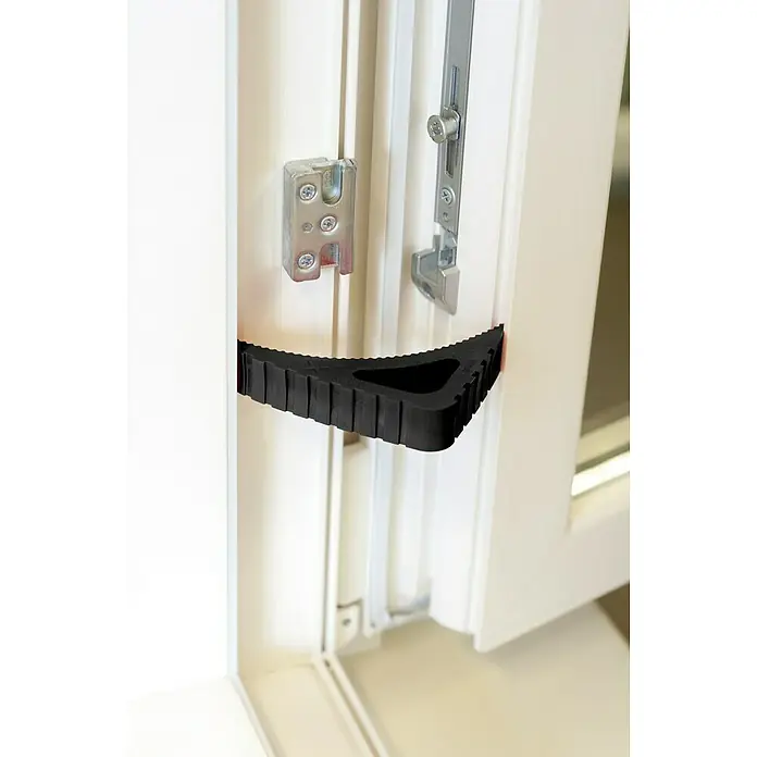Retenedor para puerta y ventana Blockystar - Negro - Un tope de puerta negro mantiene una puerta blanca abierta, mostrando los herrajes y el marco.