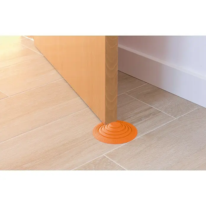 Tope de puerta y ventana Ovni Blockystar - Plástico, Ø x Al: 12 x 3 cm, Naranja - Un tope de puerta naranja en forma de cono mantiene una puerta abierta sobre un suelo de baldosas.