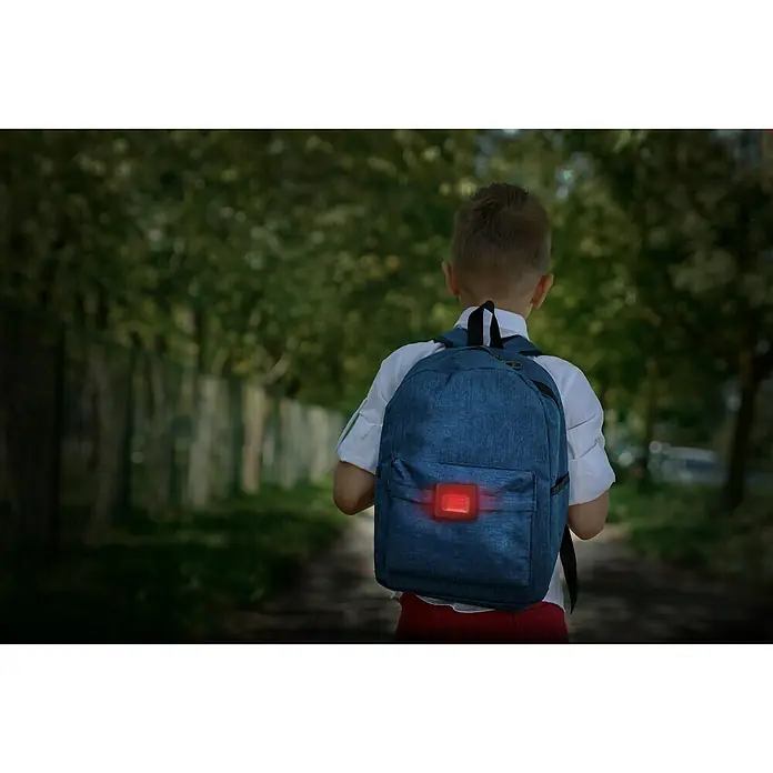 BAUHAUS Taschenlampe - Schwarz/Rot, Höhe: 2,5 cm - Junge mit blauem Rucksack mit rotem Blinklicht. Der Rucksack sorgt für erhöhte Sicherheit im Straßenverkehr für Kinder auf dem Schulweg.