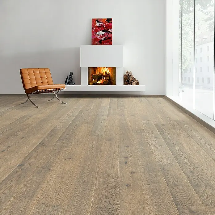 Living by Haro Parkett - Eiche Tabak Retro, Landhausdiele, 2.200 x 180 x 13,5 mm - Heller Raum mit einem modernen Kamin und Parkettboden. Ein orangefarbener Sessel steht daneben. Kunst und Holzscheite schmücken den Kamin.