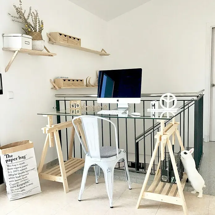 Astigarraga Holzbock Architekt - Tragkraft: 400 kg, Höhe: 70 cm, Kiefer, Natur - Ein minimalistischer Arbeitsplatz mit einem iMac auf einem Glastisch mit Holzböcken, einem weißen Stuhl und einem weißen Kaninchen.