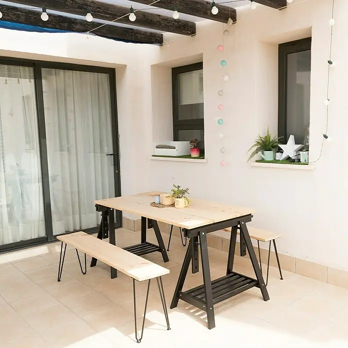 Astigarraga Holzbock Architekt - Tragkraft: 400 kg, Höhe: 70 cm, Kiefer, Schwarz - Gemütlicher Essbereich im Freien mit Holztisch und Bänken auf einem sonnigen, gefliesten Hinterhof, beleuchtet mit dekorativen Lichterketten.