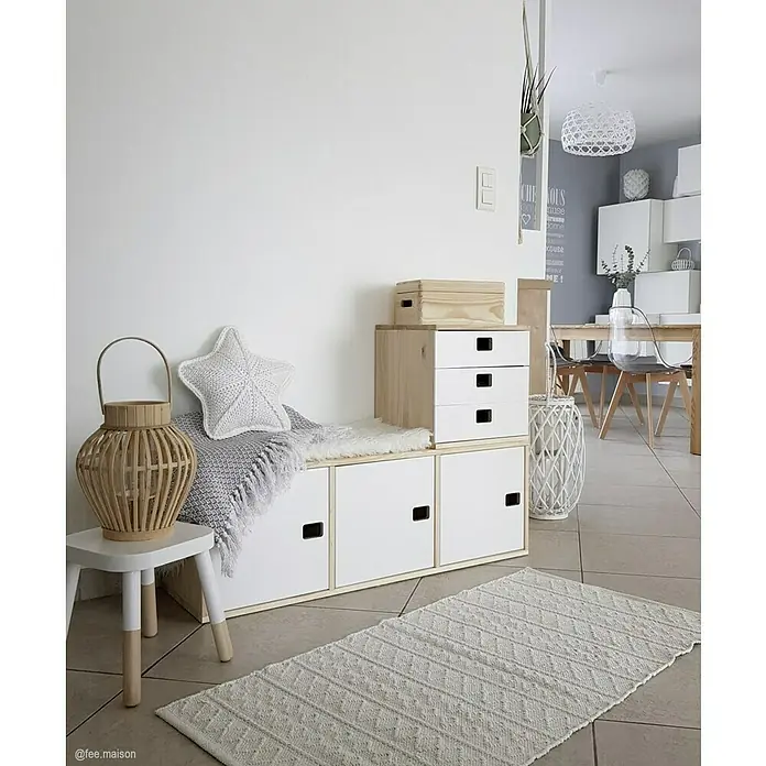 Astigarraga Dinamic Möbeltür - L x B x H: 36,2 x 32,5 x 1,6 cm, Kiefernholz - Gemütliche Ecke mit weißem Teppich, Holzkommode und dekorativen Elementen wie Laterne, Kissen und Decke.