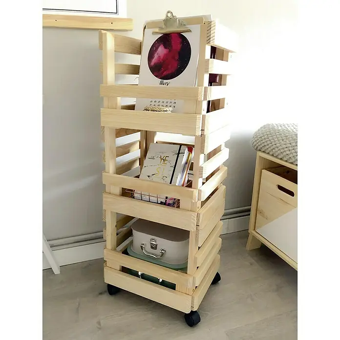 Astigarraga Evolution Carro de cocina - L x An x Al: 30 x 38 x 90 cm, Natural - Una estantería de madera con ruedas de cuatro niveles, llena de libros, cuadernos y artículos decorativos, se encuentra en un suelo claro.