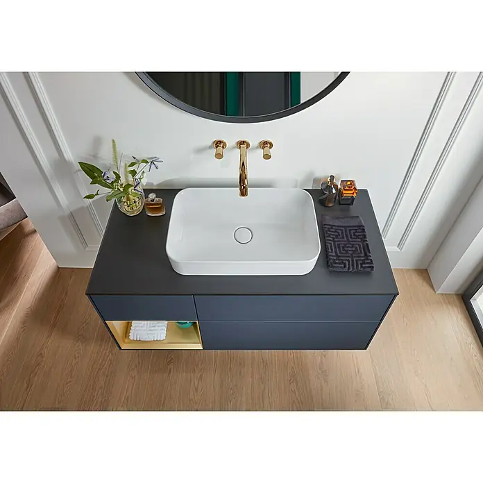 Villeroy & Boch Finion Aufsatzwaschbecken - 60 x 35 cm, Mit schmutzabweisender Glasur, Hahnloch: Ohne, Ohne Überlauf, Weiß - Das Bild zeigt ein modernes Badezimmerwaschbecken mit Unterschrank, einer Armatur in Goldoptik und einem runden Spiegel.