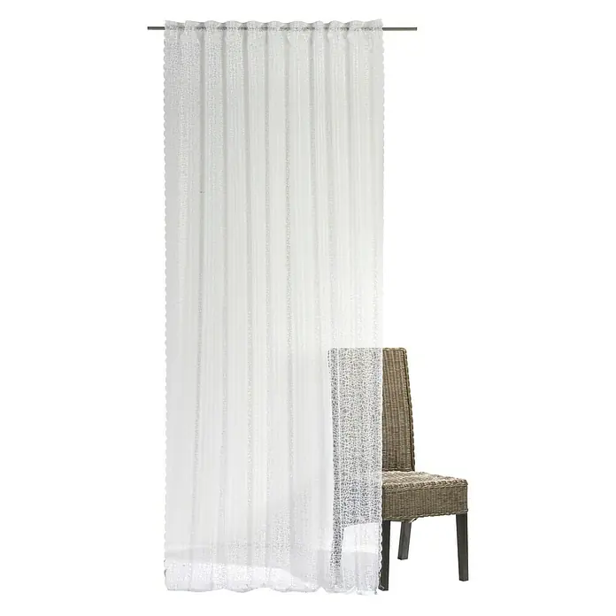 Elbersdrucke Schlaufenbandschal Membran - 100 % Polyester, Weiß, 140 x 255 cm - Ein transparenter weißer Gardinenschal mit zartem Muster hängt dekorativ vor einem Korbstuhl und sorgt für eine helle und freundliche Atmosphäre.