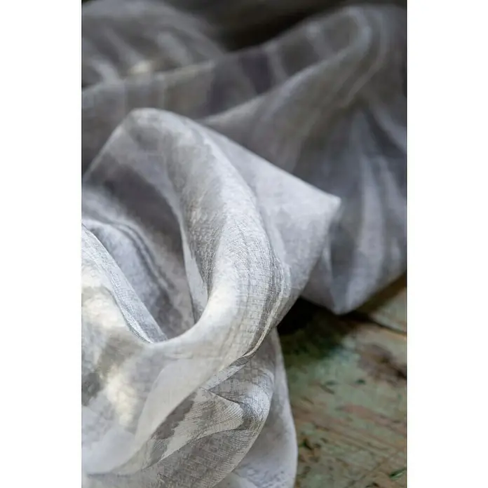 Rasch Home Schlaufenbandschal Tahiti - 140 x 255 cm, 100 % Polyester, Grau/Grün - Nahaufnahme eines drapierten, transparenten Stoffes in Grau- und Weißtönen, der eine elegante Textur und ein zartes Muster zeigt.