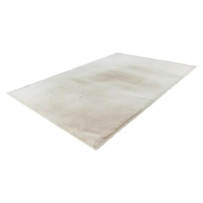 Fellteppich Happy - Beige, 230 x 160 cm, 100 % Polyester (Flor) - Ein cremefarbener Teppich liegt auf einem schwarzen Hintergrund. Das Licht betont die weiche Textur und das schlichte Design.