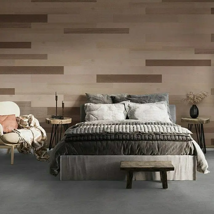Indo Wandpaneel Barnwall Lombardy - Shorea, 1.200 x 120 x 10 mm, 0,864 m² - Schlafzimmer mit Holzwandpaneelen. Das Bett ist mit grauer Bettwäsche, Kissen und einer Steppdecke dekoriert. Ein Stuhl und Holztische ergänzen den Raum.