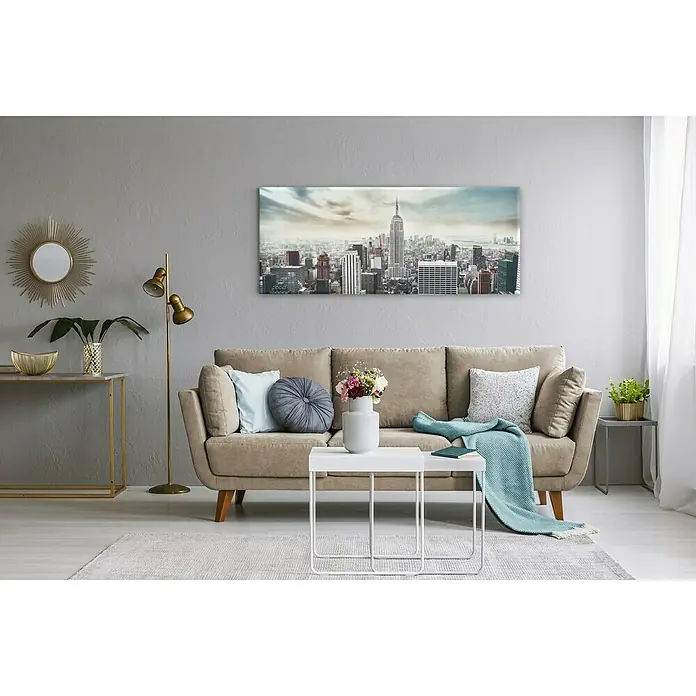 Glasbild - Manhattan, B x H: 125 x 50 cm - Ein modernes Wohnzimmer mit einem beigen Sofa, einem Couchtisch und einem Wandbild von New York City, das dem Raum eine stilvolle Note verleiht.