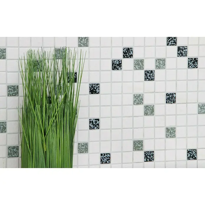 Mosaikfliese Quadrat Mix TD 180N - 30,5 x 30,5 cm, Weiß/Schwarz, Glänzend - Detailaufnahme einer Wand mit weißen Mosaikfliesen, die durch grüne und blaue Akzentfliesen sowie ein Grasbüschel aufgewertet wird.