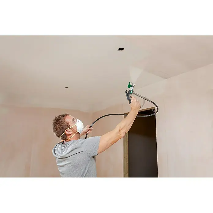 Wagner High Efficiency Airless Sistema de pulverización de pintura Airless Hea 250M - 550 W, Caudal: 1,25 l/min - Un hombre con máscara está usando un rociador de pintura para pintar un techo, con equipo profesional para un acabado uniforme.