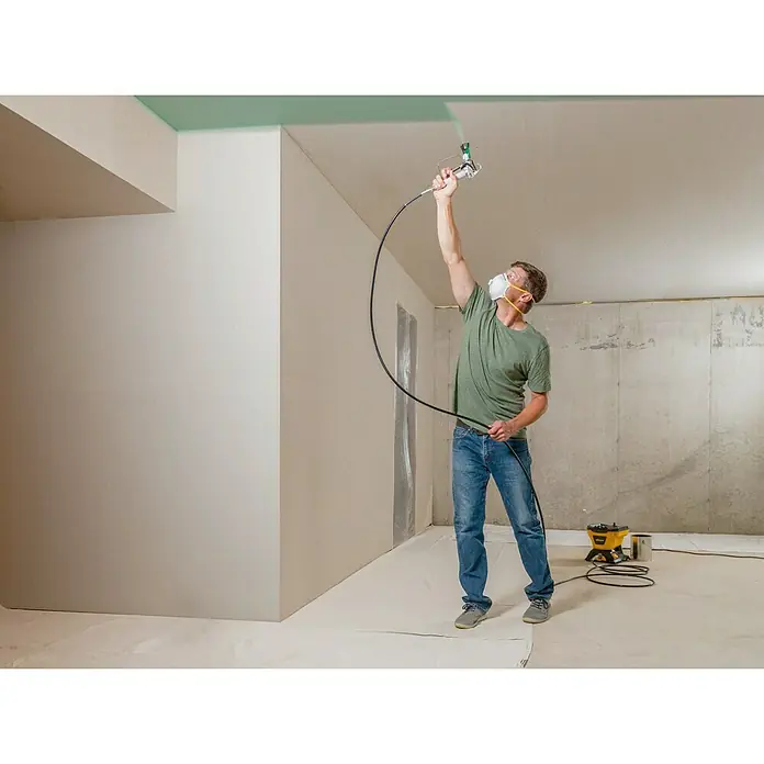 Wagner High Efficiency Airless Sistema de pulverización de pintura HEA 150M - 350 W, Caudal: 0,9 l/min - Un hombre está utilizando un pulverizador de pintura para pintar un techo, el aparato garantiza una capa uniforme de pintura.