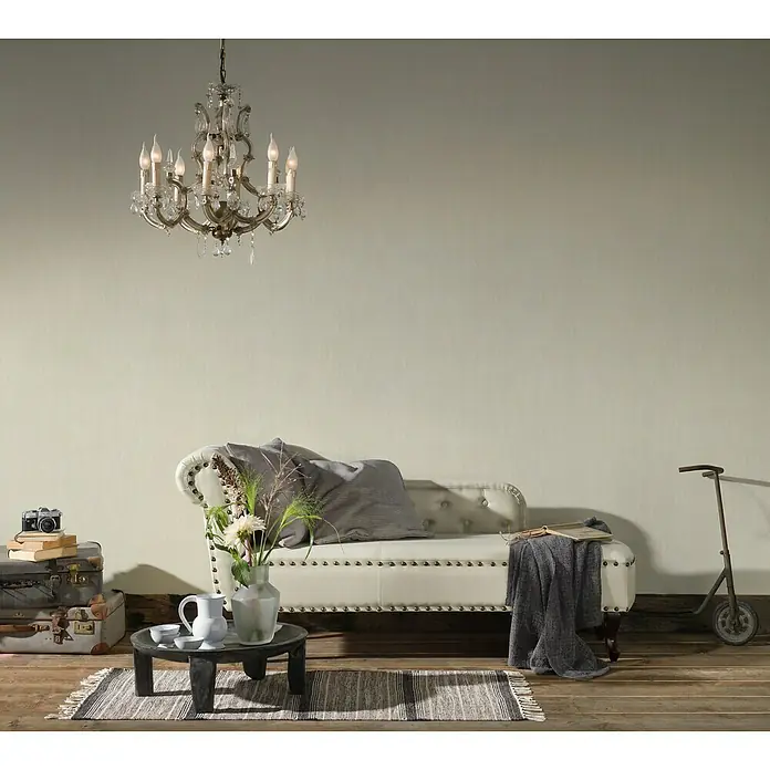 A.S. Création Romantico Vliestapete IV - Weiß, Uni, 10,05 x 0,53 m - Elegante Wohnzimmeraufnahme mit Kronleuchter, weißer Couch und dekorativen Elementen. Ideal für stilvolle Interieurs und Wohnraumgestaltung.