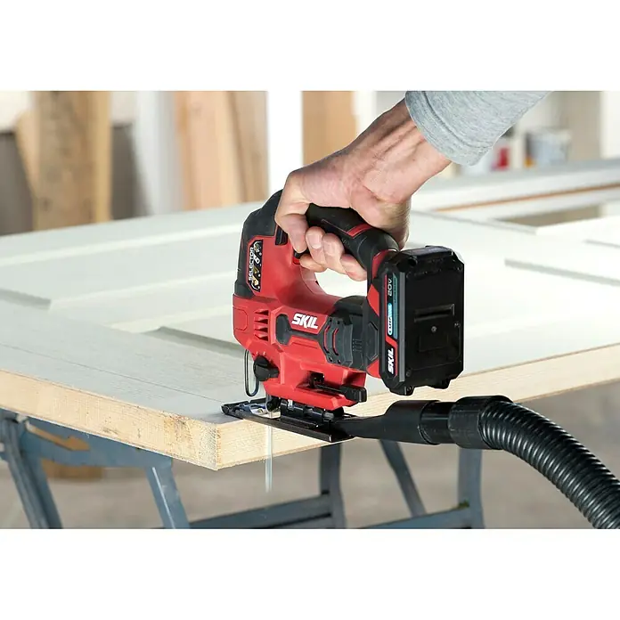 Skil PWRCore 20V Akku-Pendelhubstichsäge 3420 CA - 20 V, Ohne Akku, Leerlaufhubzahl: 0 /min - 2.800 /min - Akkubetriebene Stichsäge in Rot der Marke Skil beim Sägen eines Werkstücks.