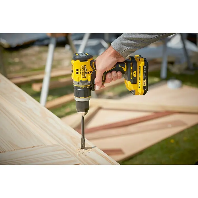 Stanley FatMax Taladro atornillador percutor de batería SFMCD721D2K -  - Primer plano de un taladro inalámbrico Stanley Fatmax perforando una tabla de madera, perfecto para proyectos de bricolaje.