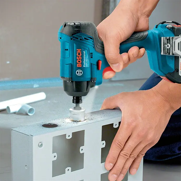Bosch Professional AMPShare 18V Llave de impacto giratoria de batería GDR18-160 - 18 V, 2 baterías, 2 Ah - Un atornillador de impacto inalámbrico azul Bosch Professional GDX 18V-200 con broca está taladrando un agujero en una caja de metal.