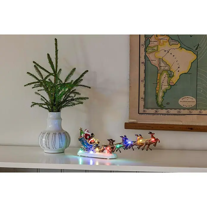 Konstsmide LED-Szenerie Weihnachtsmann/Rentiere - L x B x H: 35,5 x 6,5 x 14 cm, Bunt, Batteriebetrieben, LED - Eine festliche Szene mit einem beleuchteten Santa-Schlitten, einer stilvollen Vase und einer Karte von Südamerika.