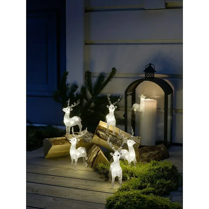 Konstsmide LED-Weihnachtsdekoleuchte LED Acryl - 4 m x 13 cm x 19 cm, Weiß, Netzbetrieben, LED - Festliche Szene mit leuchtenden Rentierfiguren, Holzscheiten, Moos und einer Laterne, die eine warme, weihnachtliche Atmosphäre schafft.