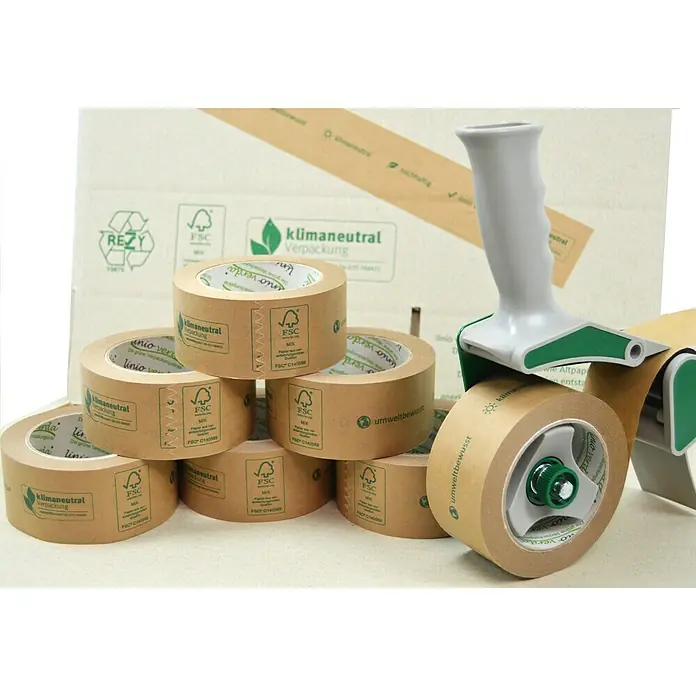 PackMann linio verda® Packband - Braun, L x B: 50 m x 50 mm - Foto von einer Auswahl an umweltfreundlichem Verpackungsmaterial, darunter Packbandrollen und ein Abroller.