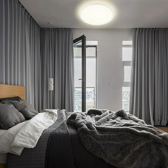 Briloner Lámpara LED decorativa Backlight - 22 W, Ø x Al: 42 x 2,9 cm, Blanco, Blanco neutro - Dormitorio con cama, edredón gris y lámpara de techo redonda para una iluminación agradable. La luminaria es moderna y discreta.