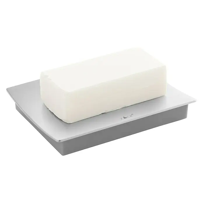 Zack Seifenschale Tenno - Edelstahl, Matt - Ein rechteckiger Block aus weißer Seife liegt auf einer grauen Seifenschale. Das Produkt ist minimalistisch und sauber gestaltet.