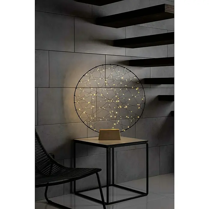 Konstsmide LED-Weihnachtsdekoleuchte LED Metallsilhouettering Holzfuß - 5 x 60 x 64 cm, Schwarz, Netzbetrieben, LED - Nahaufnahme einer kreisförmigen, modernen Lampe auf einem Tisch, die ein warmes Licht ausstrahlt. Minimalistisches Design mit dekorativer Beleuchtung.