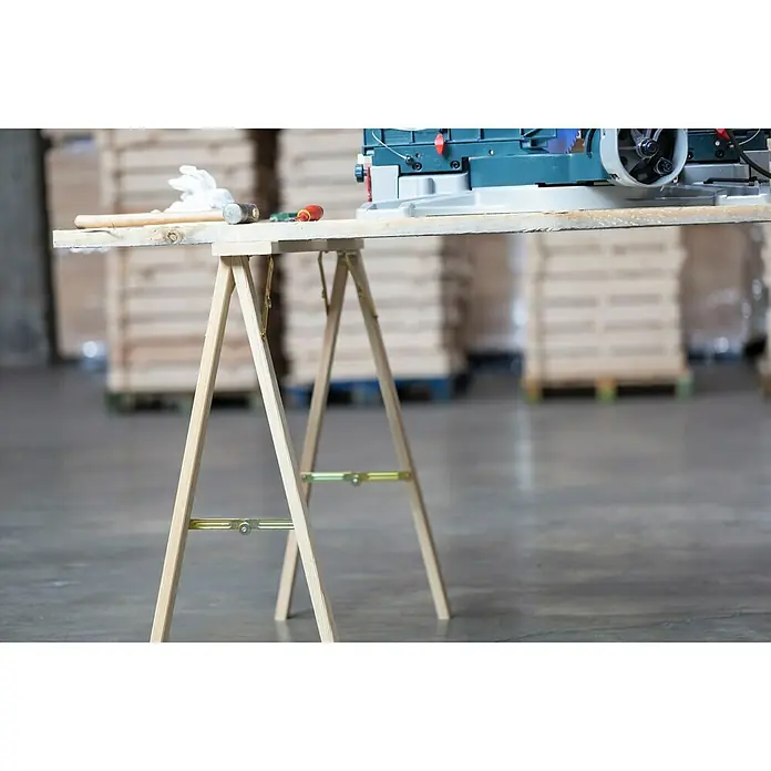 Astigarraga Holzklappbock Kipli - Tragkraft: 250 kg, Höhe: 73,5 cm, Kiefer - Eine Arbeitsbock-Szene mit Werkzeugen auf einem Holztisch und einer Säge, ideal für Werkstatt- und Bauprojekte.