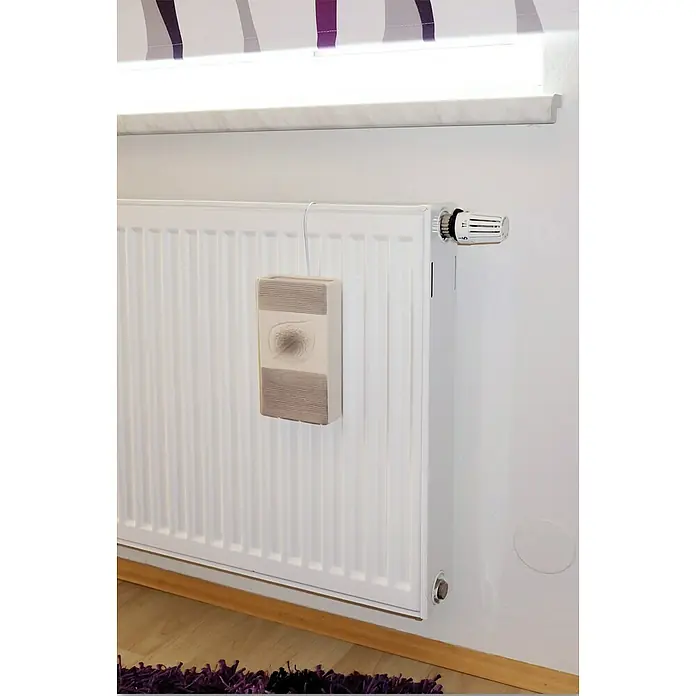 Lienbacher Heizkörperverdunster - Beige, Keramik, Relief - Detailansicht eines Heizkörpers mit Thermostat und einem an der Wand hängenden, dekorativen Lufterfrischer.