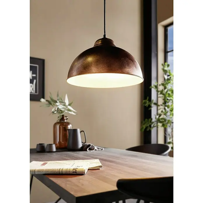 Eglo Pendelleuchte rund - Höhe: 110 cm, Kupfer - Eine Pendelleuchte in Kupferoptik hängt über einem Holztisch. Das warme Licht der Lampe beleuchtet die Szene stimmungsvoll.