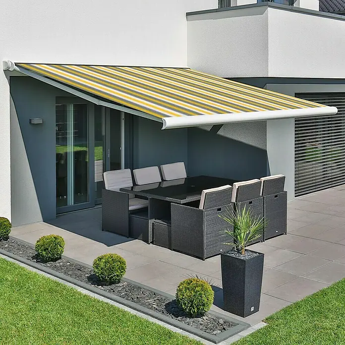 Deyo Limassol Vollkassettenmarkise - Gelb/Grau/Beige, Farbe Gestell: Signalweiß, Breite: 5 m, Ausfall: 3,5 m - Eine elegante Terrassenmarkise mit gelb-weiß gestreiften Stoff bietet Schatten über einem modernen Gartenset.