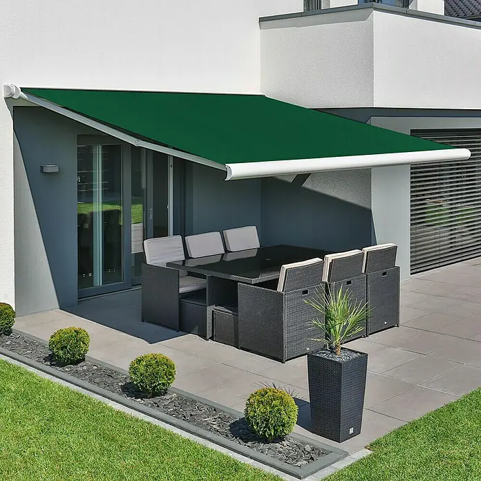 Deyo Limassol Vollkassettenmarkise - Grün, Farbe Gestell: Signalweiß, Breite: 5 m, Ausfall: 3,5 m - Das Bild zeigt eine grüne Markise, die Schatten auf eine Terrasse wirft, die mit einem Esstisch und Stühlen aus Rattanmöbeln ausgestattet ist.
