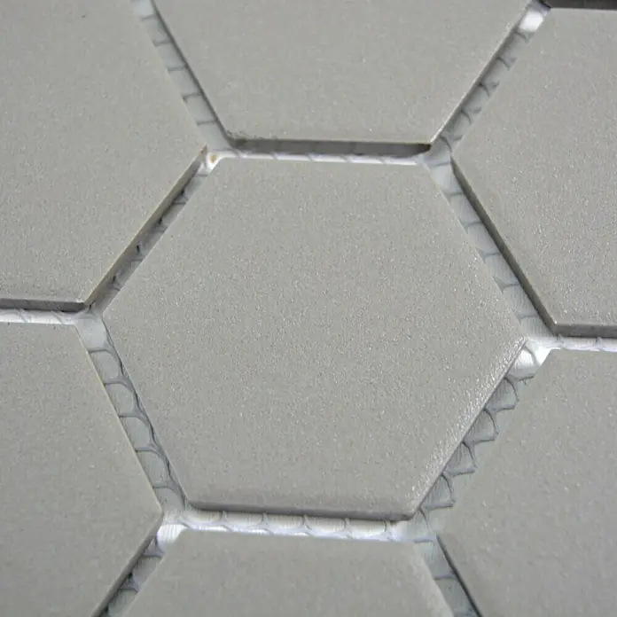Mosaikfliese Hexagon Uni CU HX127 - 32,5 x 28,1 cm, Grau, Matt - Detailansicht von grauen Sechseckfliesen, die auf einem Netz montiert sind. Ideal für moderne Wand- und Bodengestaltungen.