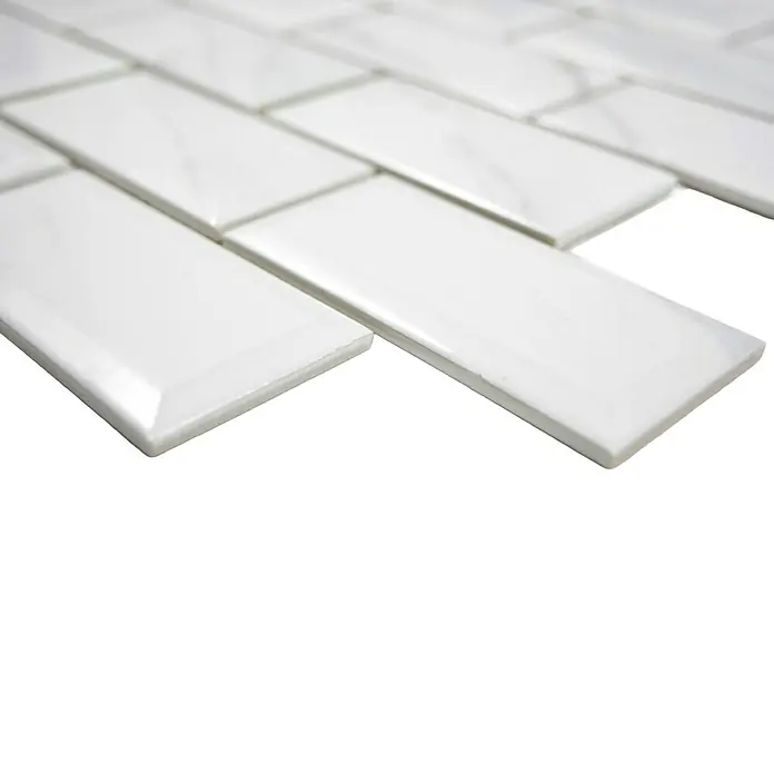Mosaikfliese Metro Uni Calacatta CG MCT - 29,55 x 29,1 cm, Weiß, Glänzend - Nahaufnahme von weißen, rechteckigen Wandfliesen, die im Fischgrätenmuster angeordnet sind, ideal für stilvolle Küchen- und Badgestaltung.