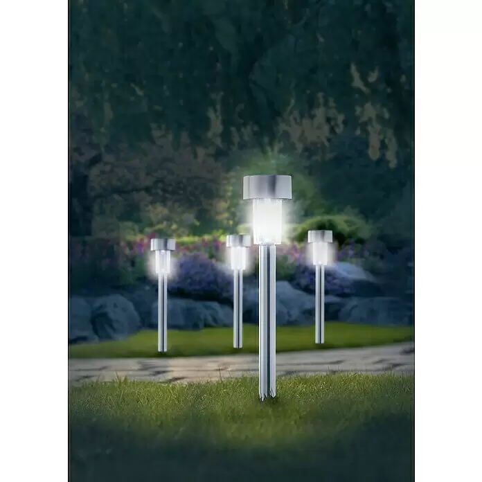 Starlux Estaca solar - 0,06 W, Plata, IP44, 4 lm - Luces solares de jardín plateadas iluminan un camino de noche, entre césped y plantas. Varias luces emiten un brillo intenso.