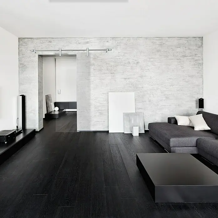 Diamond Doors Glasschiebetür Clear - 935 x 2.058 mm, Einscheibensicherheitsglas (ESG), Klarglas - Ein stilvolles Wohnzimmer mit einem schwarzen Sofa, einem schwarzen Couchtisch und einem Schiebetürenelement, das dem Raum eine moderne Note verleiht.