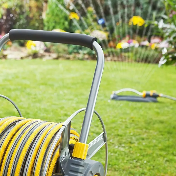 Neptun Premium Gartenschlauch - Länge: 25 m, Schlauchdurchmesser: 19 mm, ¾″, 35 bar - Gartenschlauchaufroller mit gelbem Schlauch auf einer grünen Rasenfläche. Ideal für die Bewässerung im Garten.