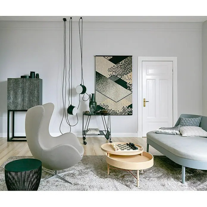 SCHÖNER WOHNEN-Farbe MyColour WandfarbeFossil, Matt, 10 l - Elegantes Interieur mit grauem Sessel, Couch und runden Tischen. Die Hängelampen und das geometrische Wandbild setzen moderne Akzente.